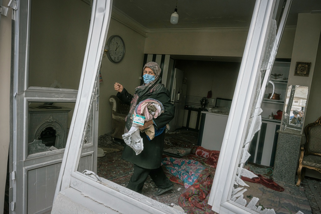 A woman collects belongings from a house damaged when a nearby residential building was hit in an overnight strike during the U.S.-Israeli military campaign in Tabriz, East Azerbaijan Province, northwestern Iran, Tuesday, March 24, 2026. (AP Photo/Matin Hashemi)