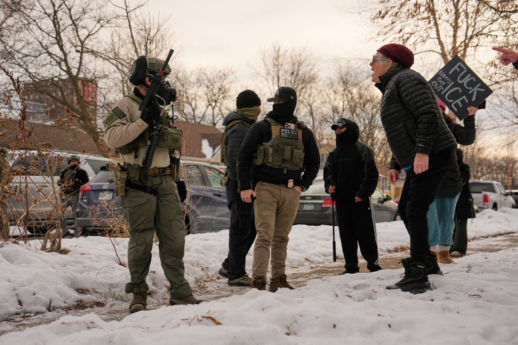 EDS NOTE: OBSCENITY - A woman yells at federal immigration officers as they make an arrest Sunday, Jan. 11, 2026, in Minneapolis. (AP Photo/John Locher)