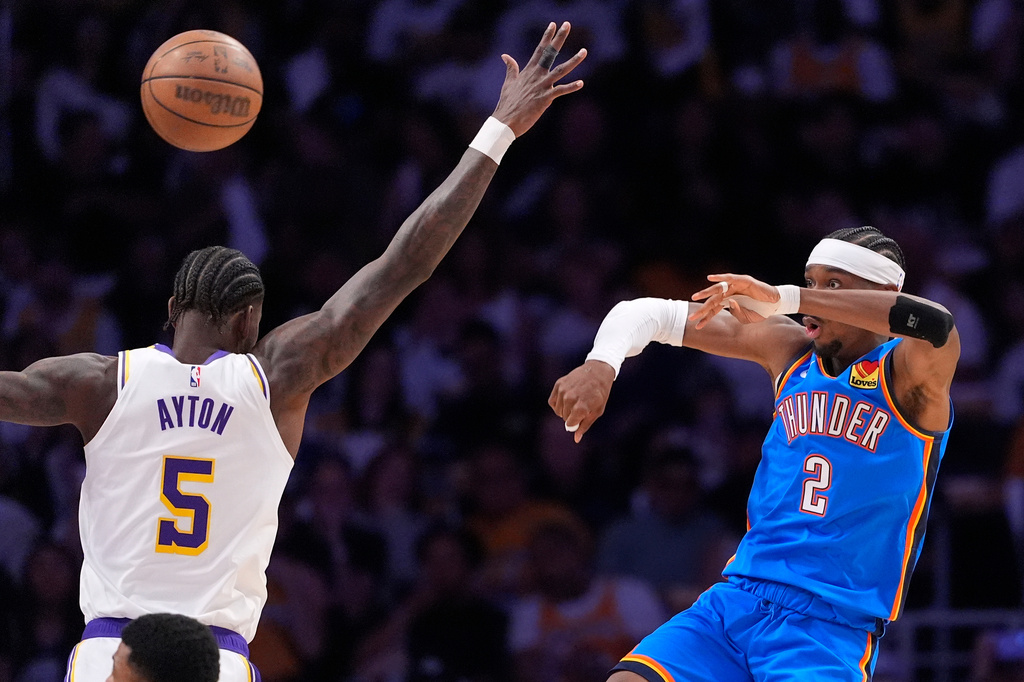 Oklahoma City Thunder guard Shai Gilgeous-Alexander, right, passes the ball as Los Angeles Lakers center Deandre Ayton defends during the first half of Game 3 in a second-round NBA basketball playoffs series Saturday, May 9, 2026, in Los Angeles. (AP Photo/Mark J. Terrill)