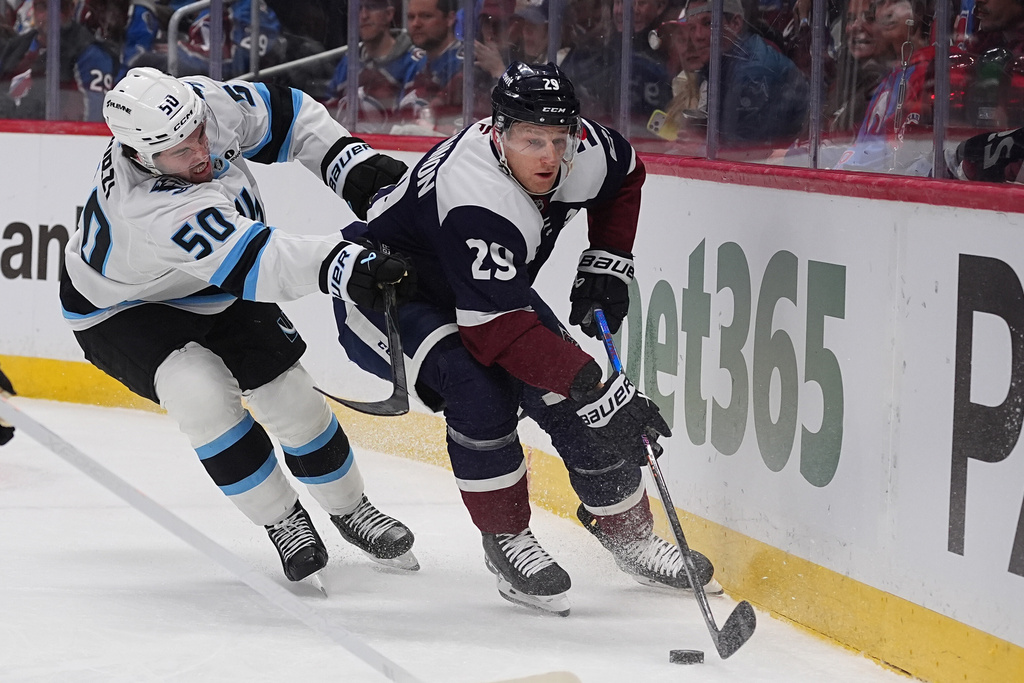 Colorado Avalanche center Nathan MacKinnon, right, drives past Utah Mammoth defenseman Sean Durzi in the first period of an NHL hockey game Tuesday, Dec. 23, 2025, in Denver. (AP Photo/David Zalubowski)