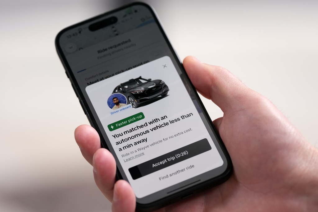A client orders an autonomous car on his mobile phone in London, Tuesday, Sept. 1, 2026 as Uber officially launches the first hailable autonomous cabs in London.(AP Photo/Frank Augstein)