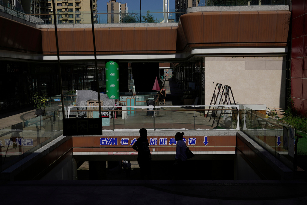 FILE -People stand in a partially shuttered Evergrande commercial complex, in Beijing, China, Aug. 25, 2025. (AP Photo/Mahesh Kumar A.), File)