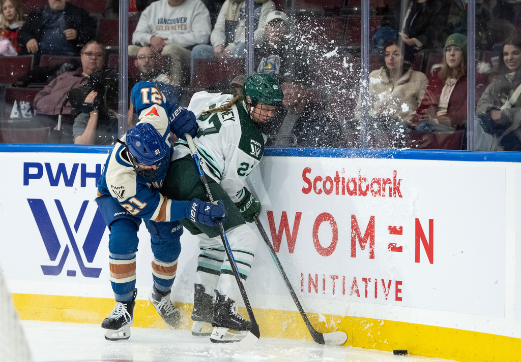 Vancouver Goldeneyes' Ashton Bell (21) and Boston Fleet's Shay Maloney (27) vie for the puck during the second period of a PWHL hockey game in Vancouver, British Columbia, Tuesday, March 10, 2026. (Ethan Cairns/The Canadian Press via AP)