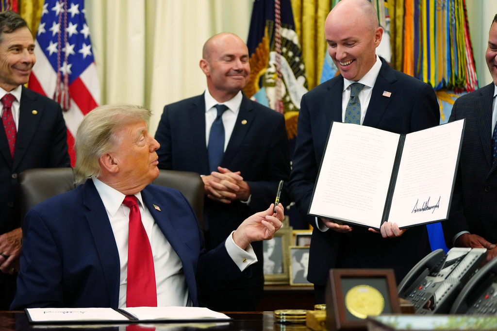President Donald Trump hands a pen to Utah Gov. Spencer Cox after signing executive orders modifying the Grand Staircase-Escalante National Monument and the Bears Ears National Monument in the Oval Office of the White House, Monday, July 13, 2026, in Washington. (AP Photo/Julia Demaree Nikhinson)