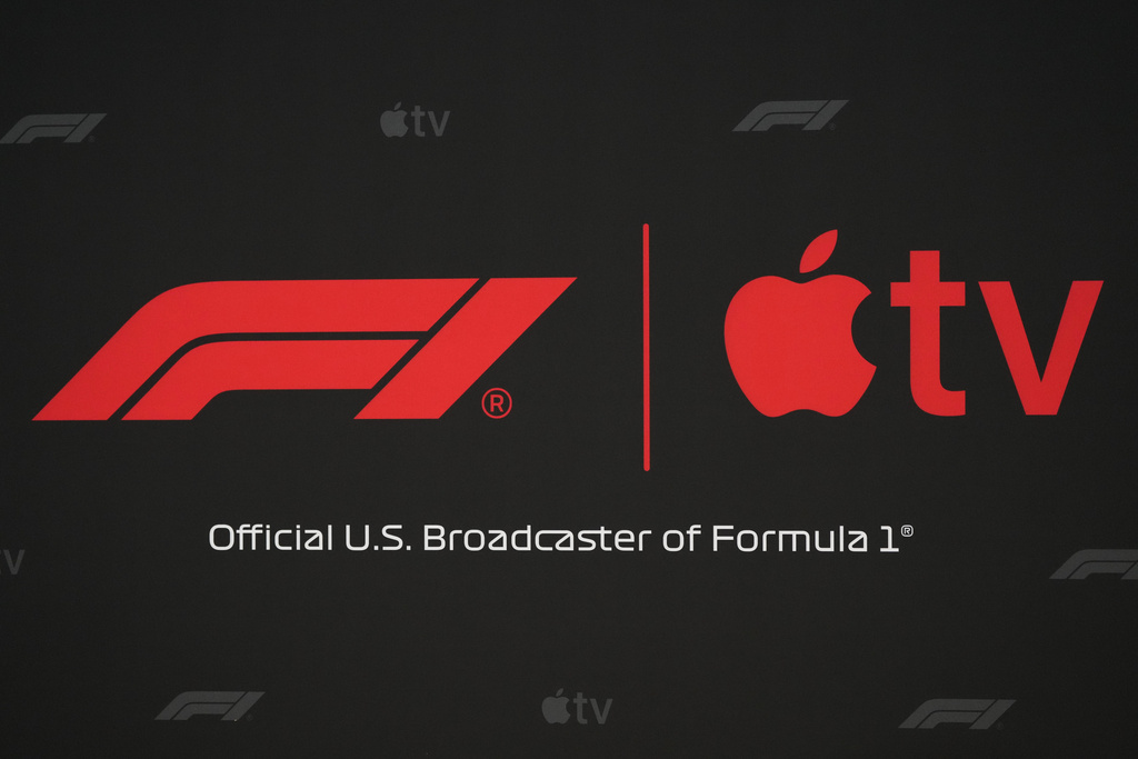 Apple and F1 logos are displayed at news conference where a five-year partnership between Formula 1 and Apple TV to bring races to Apple's streaming service beginning in 2026 was annoounced at the Circuit of the Americas in Austin, Texas, Friday, Oct. 17, 2025. (AP Photo/Eric Gay)