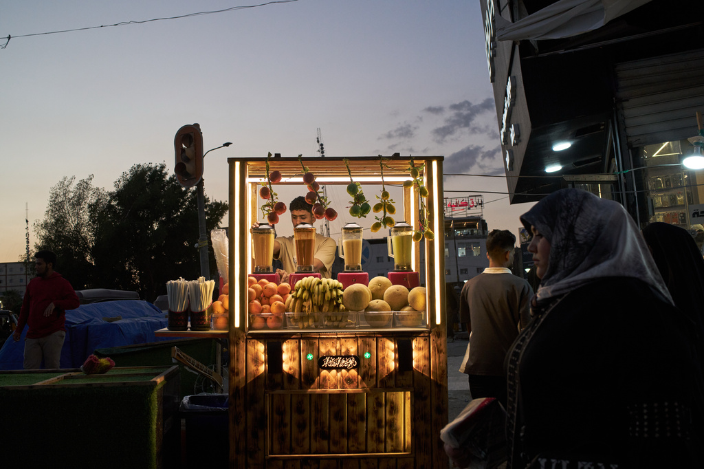 A street vendor prepares fruit juice at his stand in a street market at dusk in Basra, Iraq, Saturday, March 28, 2026. (AP Photo/Leo Correa)