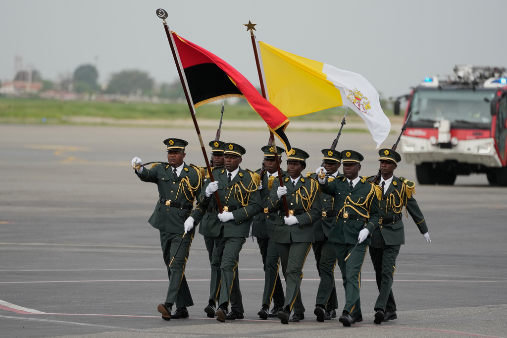 Soldiers march carrying the Vatican flag, right, and Angolan flag prior to Pope Leo XIV's departure for Equatorial Guinea, at the airport in Luanda, Angola, Tuesday, April 21, 2026. (AP Photo/Themba Hadebe)