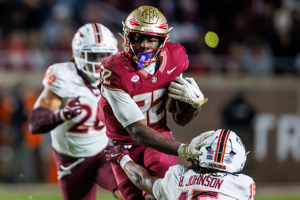 Florida State running back Ousmane Kromah, top right, pushes away from Virginia Tech safety Brennan Johnson, bottom right, as Virginia Tech linebacker Caleb Woodson, left, pursues during the second half of an NCAA college football game, Saturday, Nov. 15, 2025, in Tallahassee, Fla. (AP Photo/Colin Hackley)