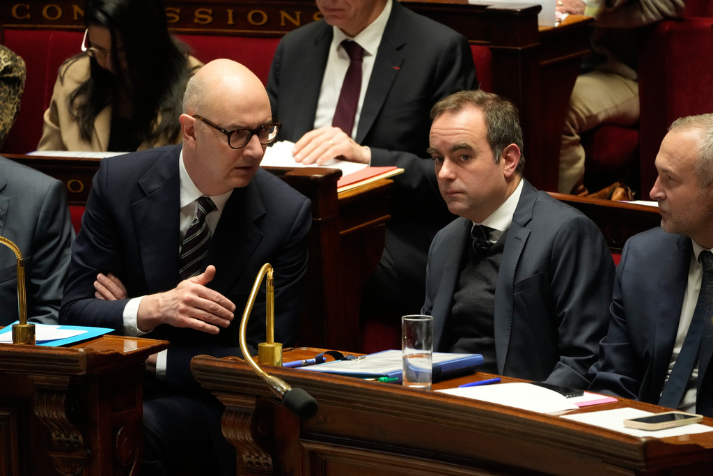 French Prime Minister Sebastien Lecornu, second right, listens to French Finance Minister Roland Lescure, left, at France's National Assembly as parliament members vote on a national health care budget that would suspend Macron's unpopular pension reform raising the retirement age, in Paris, France, Tuesday, Dec. 9, 2025. (AP Photo/Michel Euler)