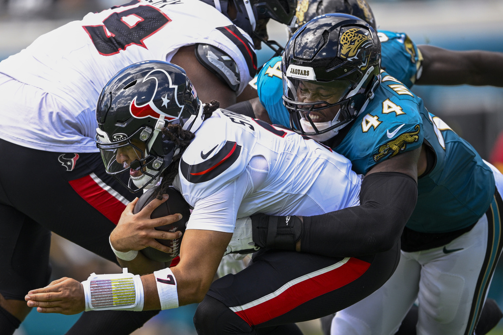 Houston Texans quarterback CJ. Stroud, left, is sacked by Jacksonville Jaguars defensive end Travon Walker during the first half of an NFL football game Sunday, Sept. 21, 2025, in Jacksonville, Fla. (AP Photo/Phelan M. Ebenhack)