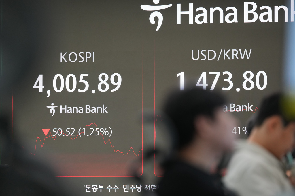 Dealers work near the screens showing the Korea Composite Stock Price Index (KOSPI), left, and the foreign exchange rate between U.S. dollar and South Korean won at a dealing room of Hana Bank in Seoul, South Korea, Thursday, Dec. 18, 2025. (AP Photo/Lee Jin-man)
