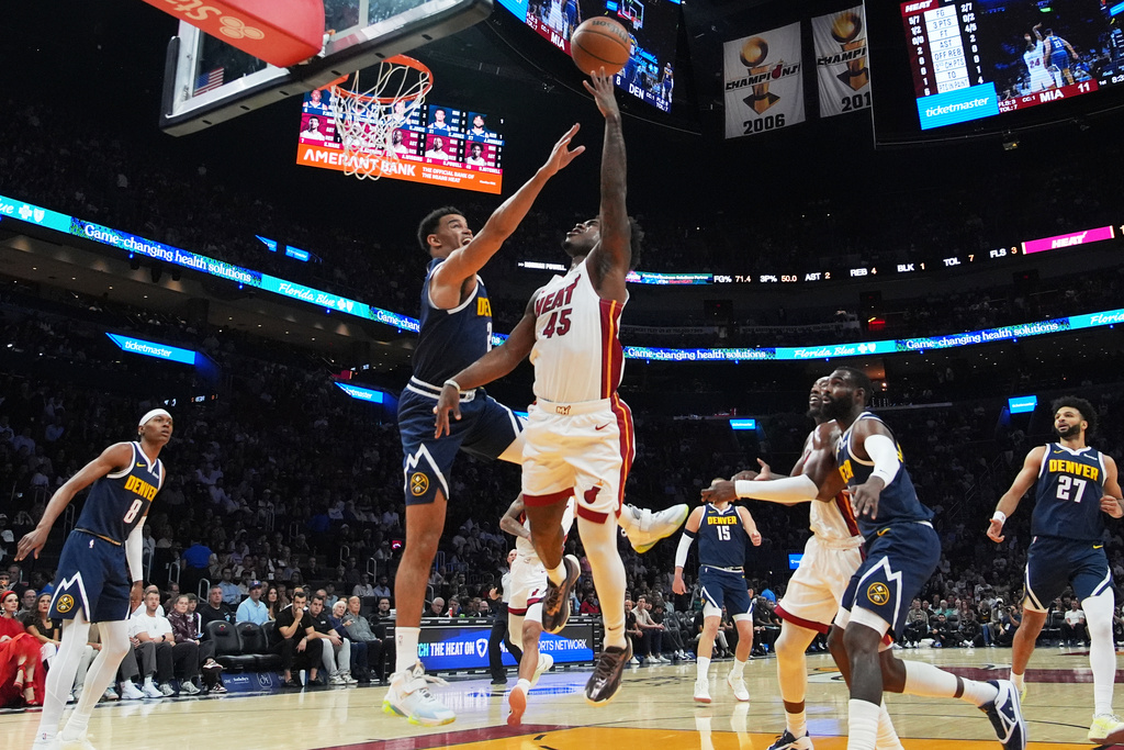 Miami Heat guard Davion Mitchell (45) goes to the basket as Denver Nuggets forward Spencer Jones, left, center, defends during the first half of an NBA basketball game, Monday, Dec. 29, 2025, in Miami. (AP Photo/Lynne Sladky)