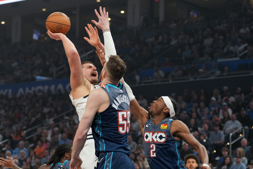 Denver Nuggets center Nikola Jokic, left, shoots over Oklahoma City Thunder center Isaiah Hartenstein, center, and guard Shai Gilgeous-Alexander (2) during the first half of an NBA basketball game, Friday, Feb. 27, 2026, in Oklahoma City. (AP Photo/Kyle Phillips)