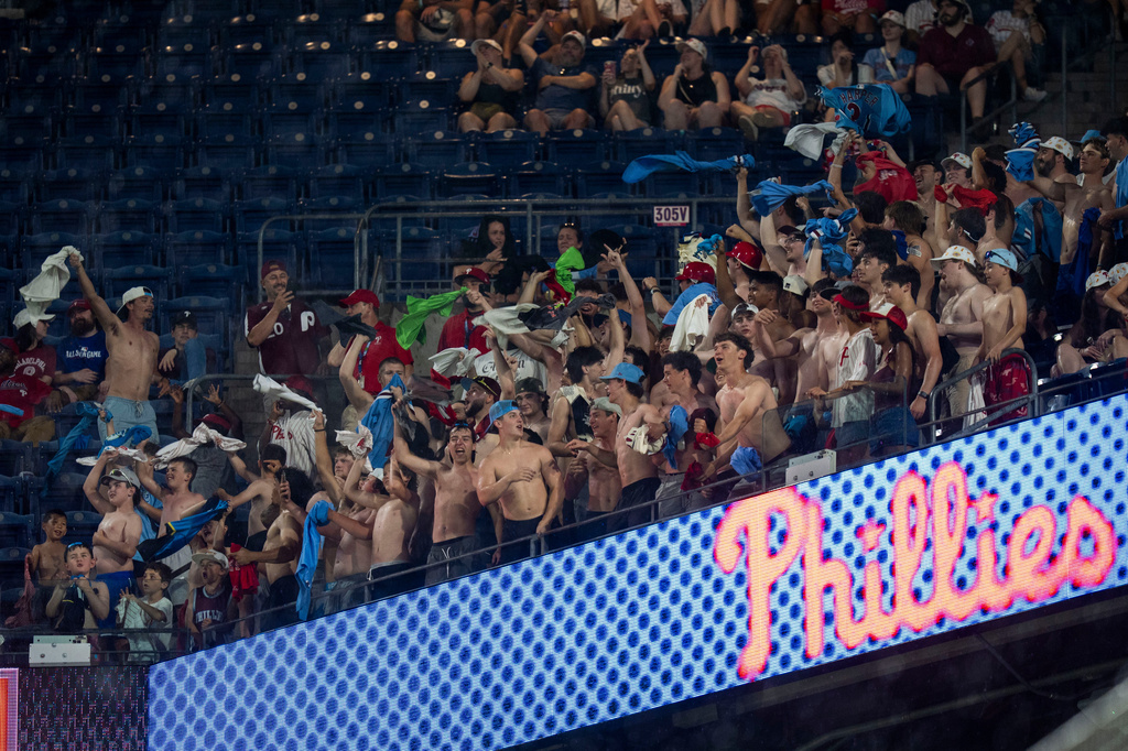 A group of fans in the upper deck wave their shirts as they go "tarps off" during the eighth inning of a baseball game between the Cincinnati Reds and the Philadelphia Phillies, Tuesday, May 19, 2026, in Philadelphia. (AP Photo/Chris Szagola)