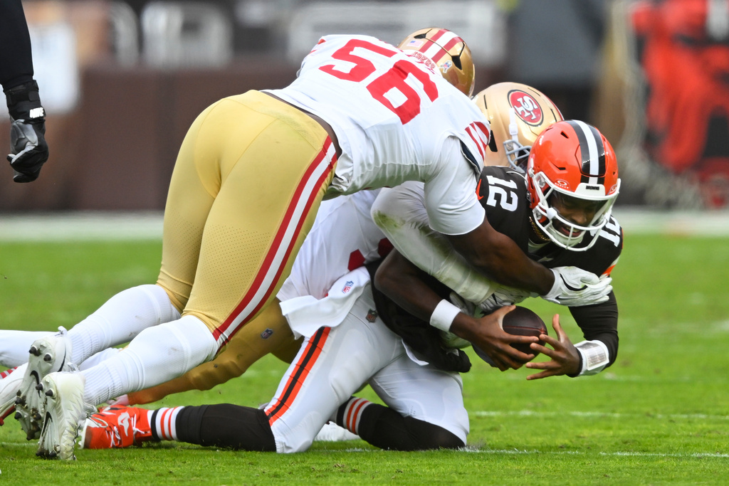 Cleveland Browns quarterback Shedeur Sanders (12) is sacked by San Francisco 49ers defensive end Clelin Ferrell, rear, as defensive lineman Keion White (56) follows the play during the first half of an NFL football game, Sunday, Nov. 30, 2025, in Cleveland. (AP Photo/David Richard)