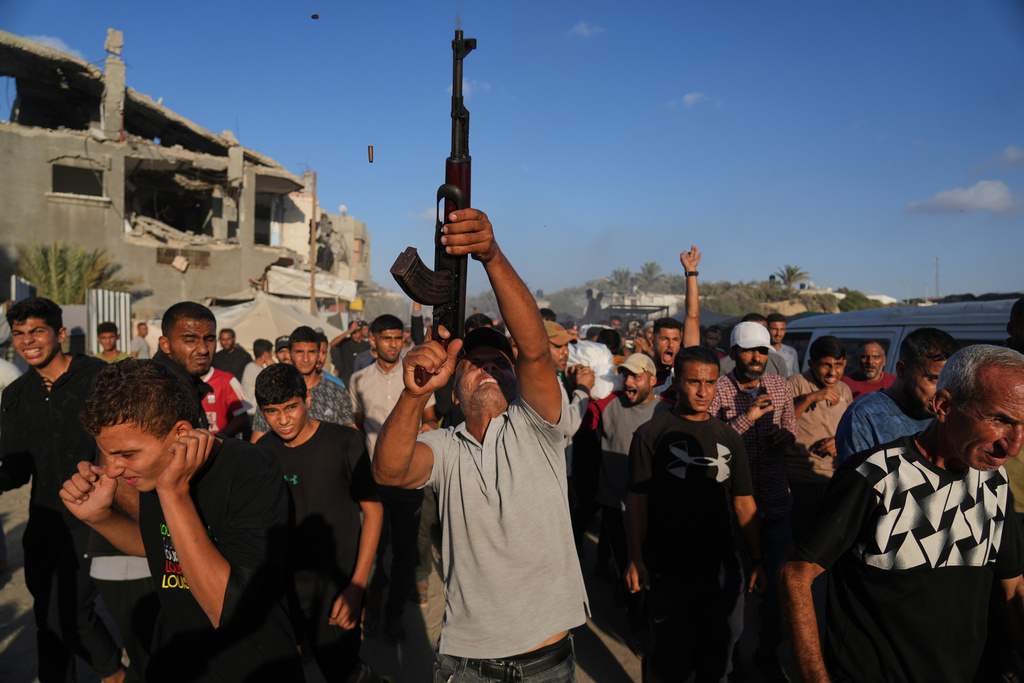 An armed man shoots in the air during the funeral of Palestinians killed by Israeli fire, in Deir al-Balah, Gaza Strip, Sunday, Oct. 19, 2025. (AP Photo/Abdel Kareem Hana)