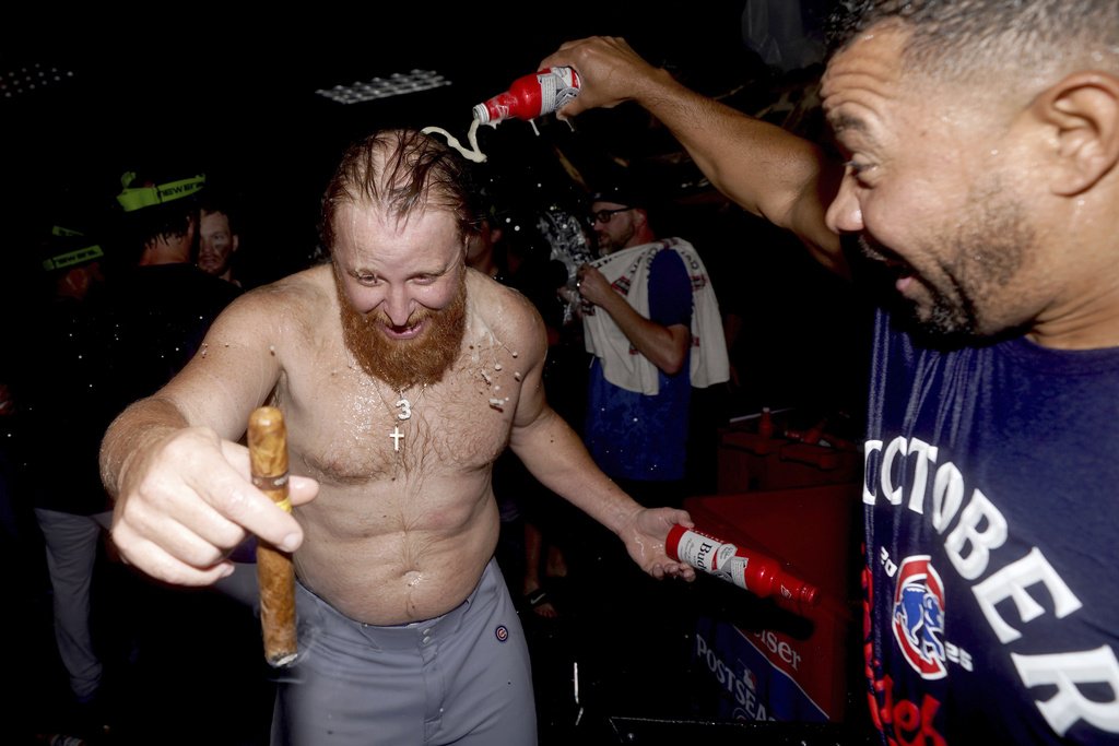 Chicago Cubs' Justin Turner, left, celebrates with assistant hitting coach Juan Cabreja, right, in the clubhouse after the Cubs clinched a playoff berth after defeating the Pittsburgh Pirates in a baseball game Wednesday, Sept. 17, 2025, in Pittsburgh. (AP Photo/Matt Freed)