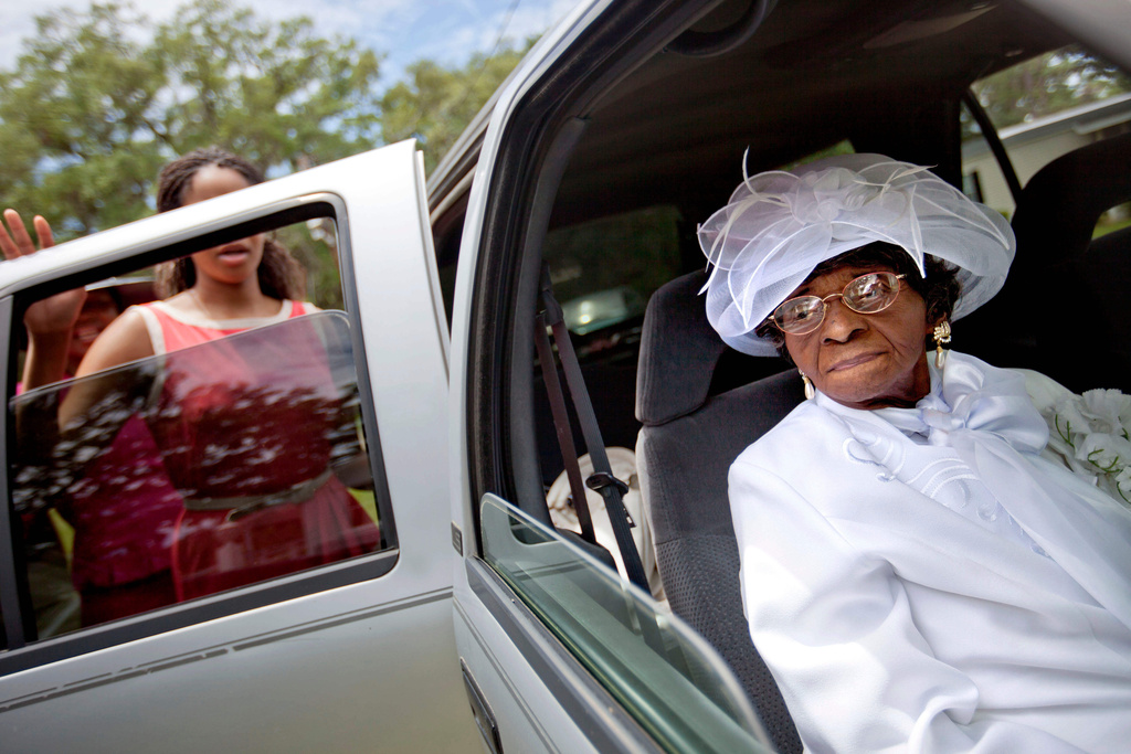 FILE - Cathleen Hillary, 93, the oldest resident of Sapelo Island, Ga. leaves a church service with her great granddaughter Milaika Ellison, for the 129th anniversary of St. Luke Baptist Church on the island on Sunday, June 9, 2013. (AP Photo/David Goldman, File)