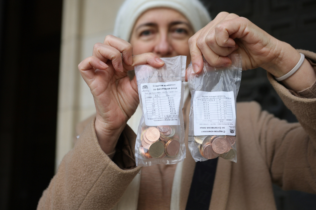 A woman poses as she holds new euro coins with Bulgarian symbols in Sofia in front of Bulgarian National Bank, Saturday Dec. 27, 2025. (AP Photo/Valentina Petrova)