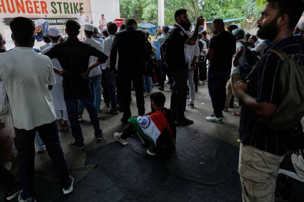 A supporter with Indian flag on his shoulder sits and listen to a speaker with others during a protest by the Cockroach Janta Party demanding the resignation of Education Minister Dharmendra Pradhan over alleged examination irregularities and repeated paper leaks, in New Delhi, India, on July 10, 2026. (AP Photo/Manish Swarup)