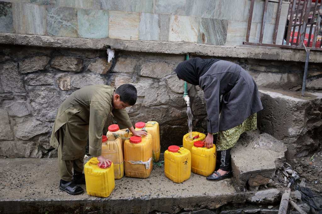 A boy and a girl collect water from a hose connected to a well at a mosque in Deh Mazang, Kabul, Afghanistan, Thursday, April 2, 2026. (AP Photo/Siddiqullah Alizai)