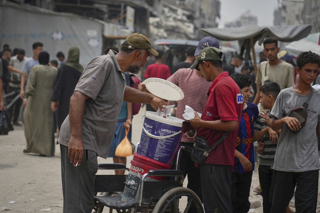 In the summer heat, a man sells plastic bags of water for one shekel each, in Gaza City, Tuesday, Aug. 12, 2025. (AP Photo/Jehad Alshrafi)