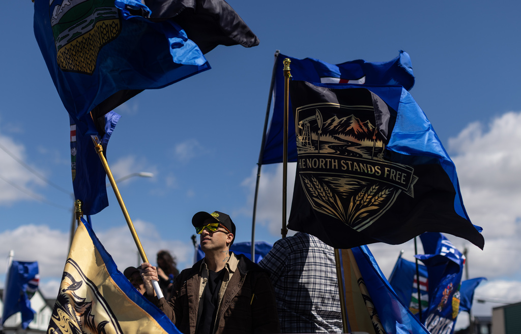 Supporters fly flags in support of Mitch Sylvestre as he submits his signatures for a separation referendum to Elections Alberta in Edmonton, on Monday, May 4, 2026. (Jason Franson/The Canadian Press via AP)