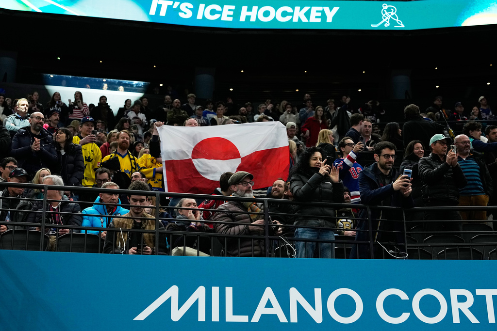 Fans hold Greenland national flag before a preliminary round match of men's ice hockey between United States and Denmark at the 2026 Winter Olympics, in Milan, Italy, Saturday, Feb. 14, 2026. (AP Photo/Petr David Josek)