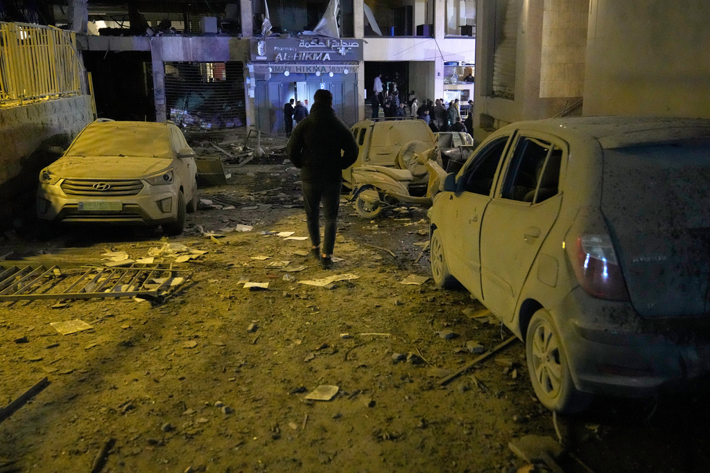 A man walks at the site of a destroyed branch of Al-Qard Al-Hassan, background, a non-bank financial institution run by Hezbollah, which was hit by an Israeli airstrike in central Beirut, Lebanon, Thursday, March 12, 2026. (AP Photo/Hussein Malla)