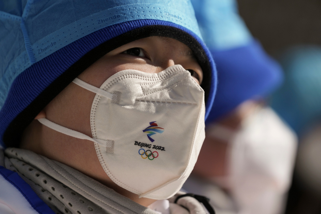 FILE - A member of the medical staff wears a protective mask as she watches a women's normal hill ski jumping training session at the 2022 Winter Olympics, Feb. 4, 2022, in Zhangjiakou, China. (AP Photo/Matthias Schrader, file)