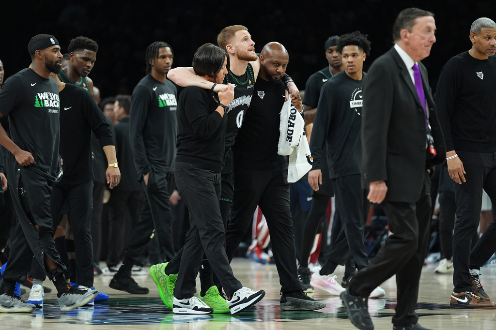 Minnesota Timberwolves guard Donte DiVincenzo (0) is helped off the court after sustaining an injury during the first half of Game 4 of a first-round NBA basketball playoff series against the Denver Nuggets, Saturday, April 25, 2026, in Minneapolis. (AP Photo/Abbie Parr)
