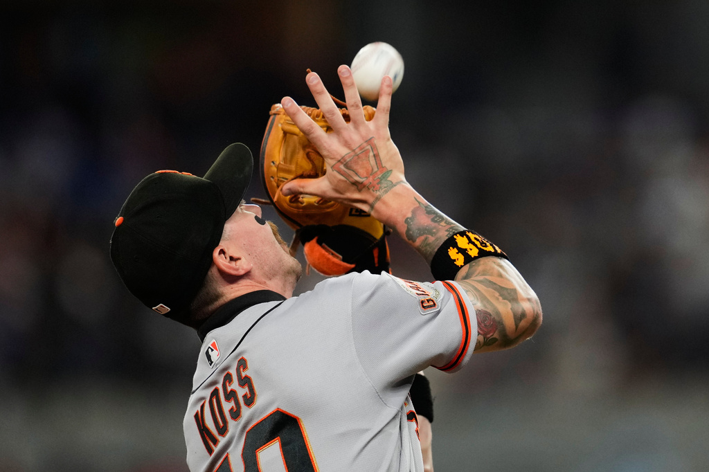 San Francisco Giants third baseman Christian Koss reaches up to catch a pop-out by Texas Rangers' Brandon Nimmo in the fifth inning a baseball game in Arlington, Texas, Tuesday, Aug. 4, 2026. (AP Photo/Tony Gutierrez)