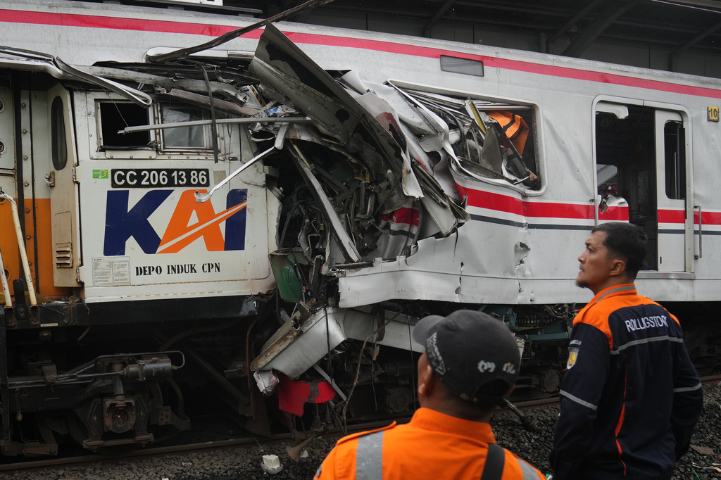 Workers examine the wreckages of trains after a collision in Bekasi, Indonesia, Tuesday, April 28, 2026. (AP Photo/Tatan Syuflana)