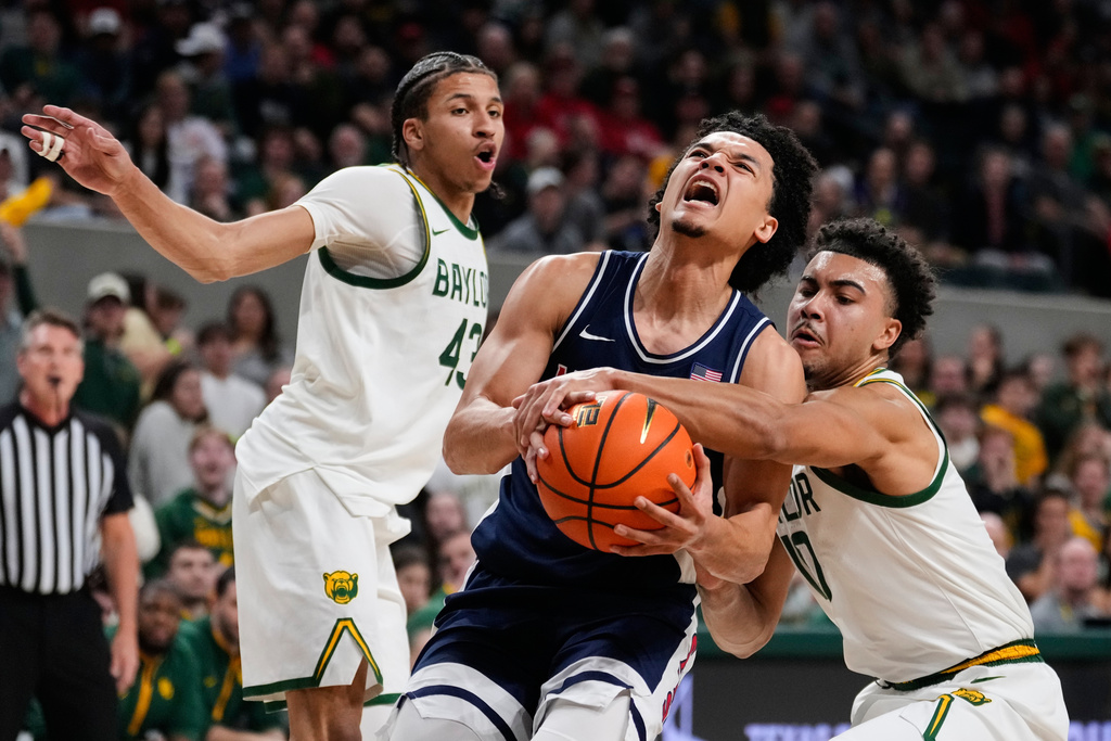 Arizona guard Brayden Burries, center, is fouled driving to the basket by Baylor's Isaac Williams (10) as Cameron Carr (43) helps defend on the play in the first half of an NCAA college basketball game, in Waco, Texas, Tuesday, Feb. 24, 2026. (AP Photo/Tony Gutierrez)