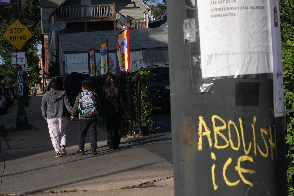 A student heads home from school past "Abolish ICE" graffiti scrawled on a post across the street from Funston Elementary School, in Chicago's Logan Square neighborhood, Tuesday, Oct. 14, 2025. (AP Photo/Rebecca Blackwell)