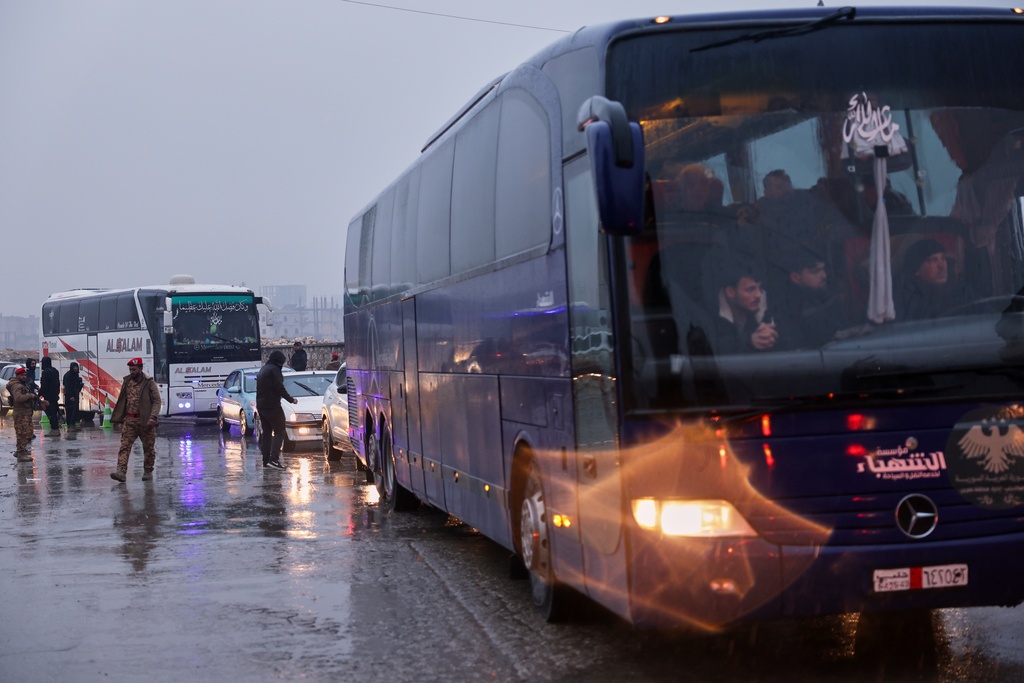 Buses carry displaced residents as they return to the Achrafieh neighborhood after days of fighting between government forces and Kurdish fighters in the northern city of Aleppo, Syria, Monday, Jan. 12, 2026. (AP Photo/Ghaith Alsayed)
