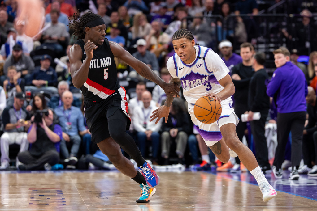 Utah Jazz guard Keyonte George (3) dribbles past Portland Trail Blazers guard Jrue Holiday (5) during the second half of an NBA basketball game, Wednesday, Oct. 29, 2025, in Salt Lake City. (AP Photo/Anna Fuder)