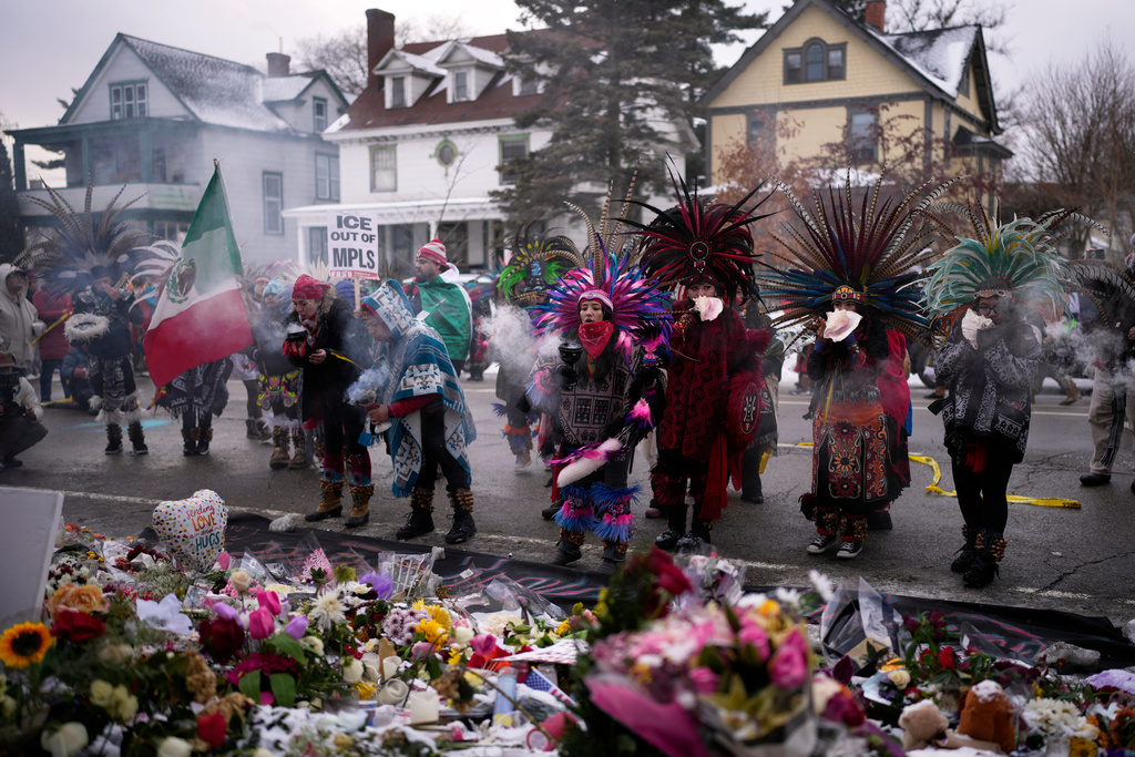 Aztec dancers stand before a makeshift memorial near the site where Renee Good was fatally shot by an ICE officer earlier in the week, in Minneapolis, Saturday, Jan. 10, 2026. (AP Photo/John Locher)