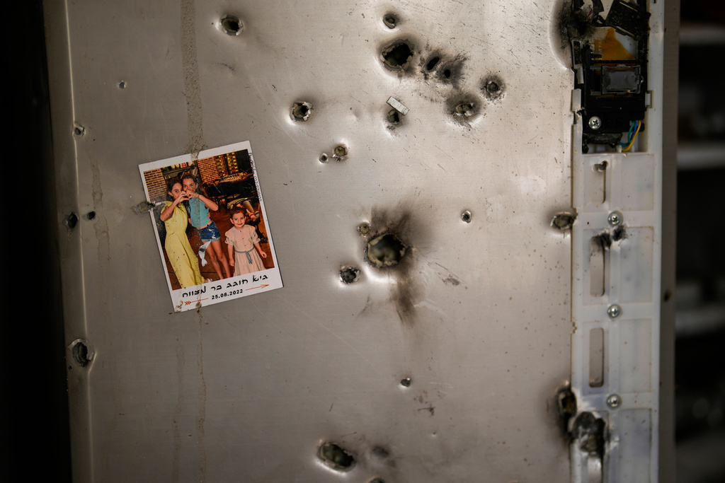 A photo hangs on a refrigerator next to bullet holes in a house at Kibbutz Kissufim in southern Israel, Saturday, Oct. 21, 2023, after the kibbutz was overrun by Hamas militants from the nearby Gaza Strip on Oct. 7. (AP Photo/Francisco Seco)