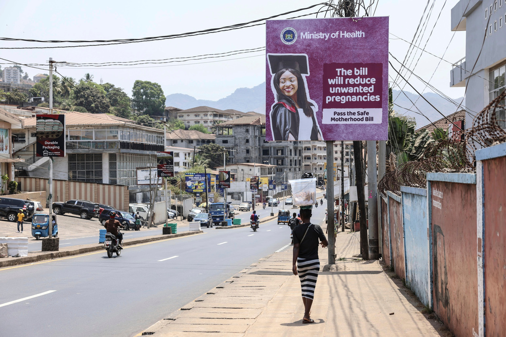 FILE - A woman walks past a billboard promoting the Safe Motherhood Bill on Wilkinson Road in Freetown, Sierra Leone, March 12, 2025. (AP Photo/Caitlin Kelly, File)