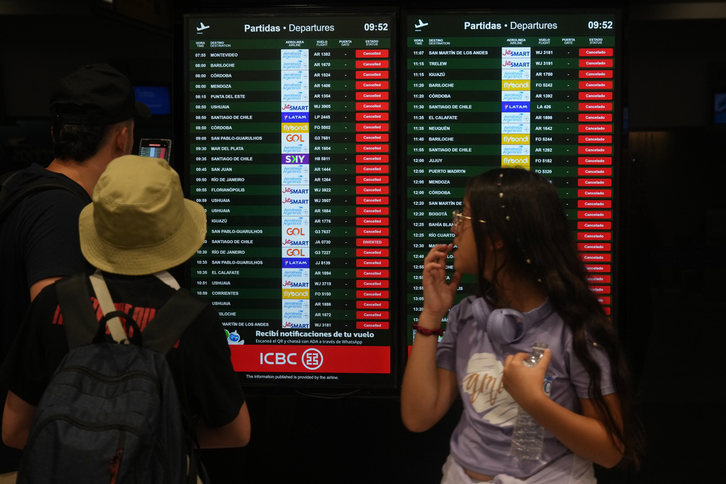 Travelers look at an information board listing canceled flights during a union strike against President Javier Milei’s proposed labor reform bill in Buenos Aires, Argentina, Thursday, Feb. 19, 2026. (AP Photo/Gustavo Garello)