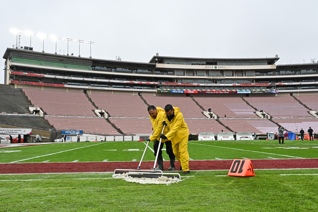 Workers clear rain water off the playing field before the Rose Bowl College Football Playoff quarterfinal game Thursday, Jan. 1, 2026, in Pasadena, Calif. (AP Photo/Kyusung Gong)