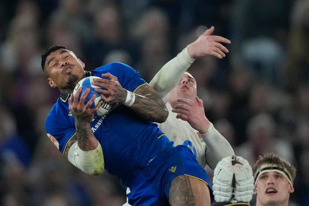 Italy's Monty Ioane, left, is challenged by England's Tommy Roebuck during the Six Nations rugby union match between Italy and England in Rome, Saturday, March 7, 2026. (AP Photo/Gregorio Borgia)