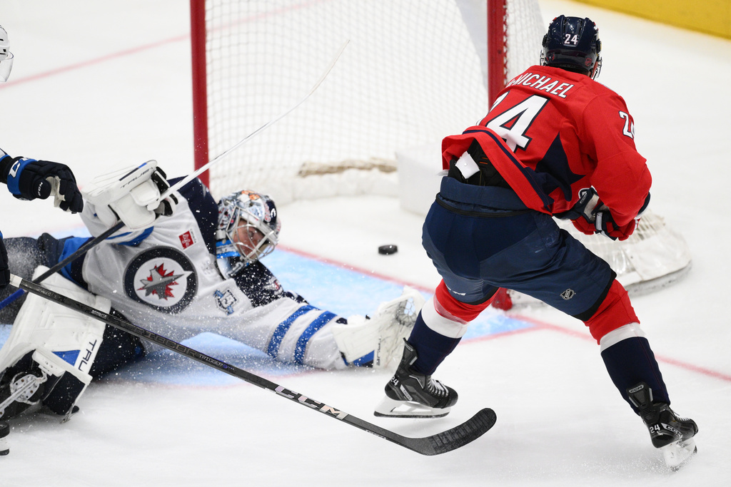Washington Capitals center Connor McMichael (24) scores a goal past Winnipeg Jets goaltender Eric Comrie (1) during the third period of an NHL hockey game, Wednesday, Nov. 26, 2025, in Washington. (AP Photo/Nick Wass)