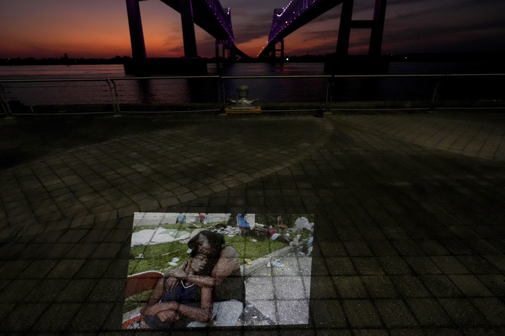 This photo showing flood victims sitting at the Ernest N. Morial Convention Center where they had been waiting for days to be evacuated in the aftermath of Hurricane Katrina in New Orleans, taken by AP photographer Eric Gay, is projected Tuesday, Aug. 26, 2025, along the Mississippi River behind the convention center. (AP Photo/Gerald Herbert)