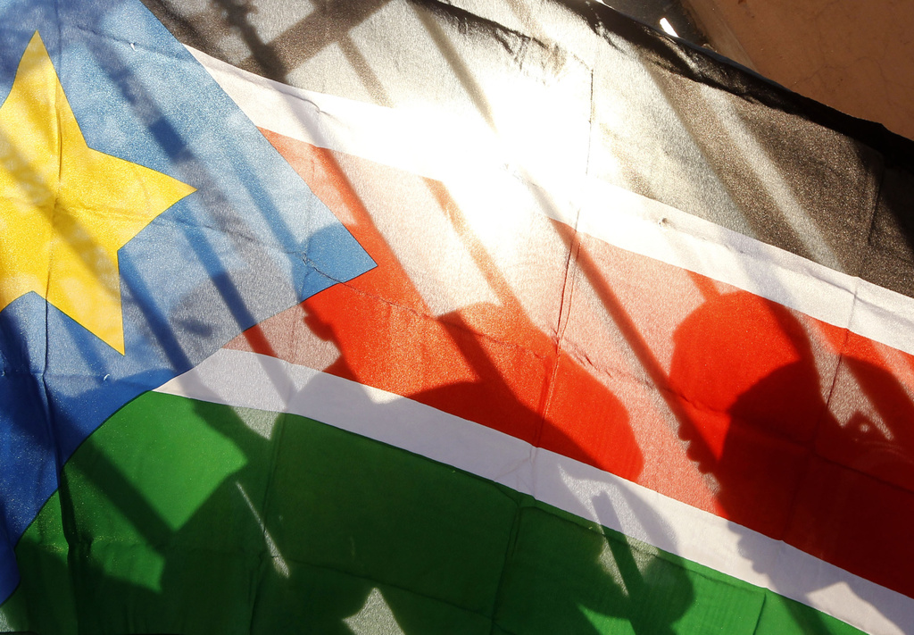 FILE - The silhouettes of South Sudanese people are seen through a South Sudanese flag as they line up to cast their votes in Juba, South Sudan, on Jan. 9, 2011. (AP Photo/Jerome Delay, File)