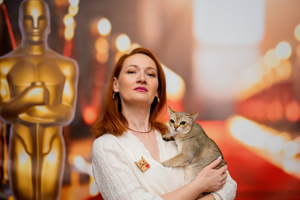 A woman poses with a Singapura cat in front of an Oscars themed photo backdrop during an international feline beauty competition, dubbed the Feline Oscars, featuring more than 200 cats in Bucharest, Romania, Saturday, March 21, 2026. (AP Photo/Andreea Alexandru)