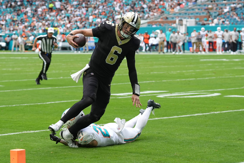 New Orleans Saints quarterback Tyler Shough (6) avoids a tackle by Miami Dolphins safety Ashtyn Davis (21) for a two-point conversion during the second half of an NFL football game Sunday, Nov. 30, 2025, in Miami Gardens, Fla. (AP Photo/Lynne Sladky)