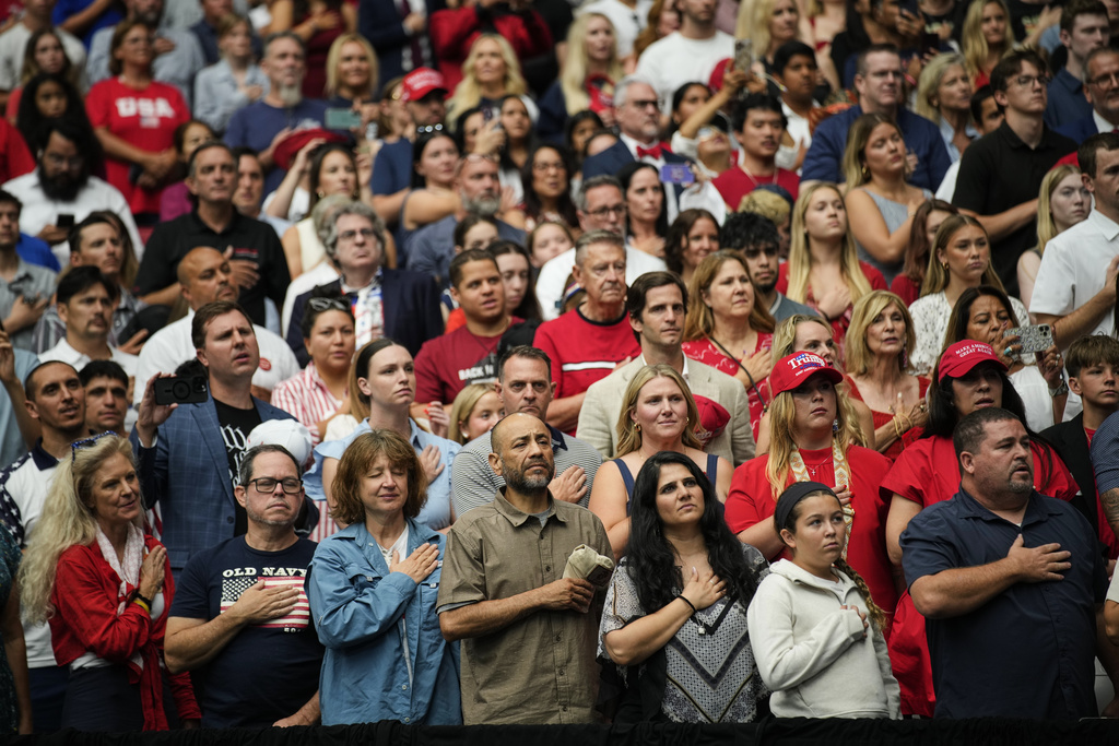 People stand for the singing of the national anthem at a memorial for conservative activist Charlie Kirk, Sunday, Sept. 21, 2025, at State Farm Stadium in Glendale, Ariz. (AP Photo/John Locher)