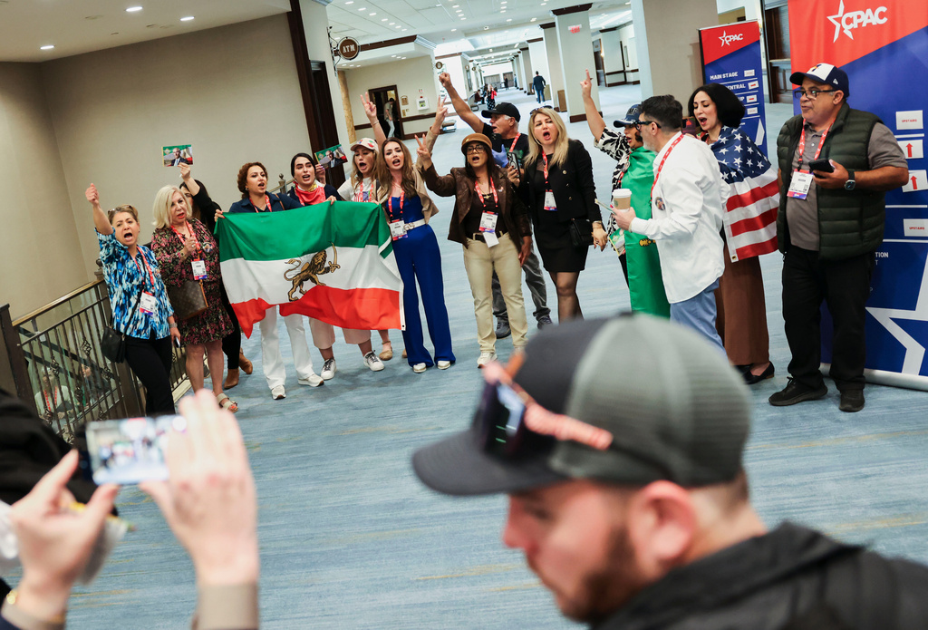 Attendees chant "Thank you Trump" outside of the exhibit hall holding the Iranian flag during Conservative Political Action Committee at Gaylord Texan Resort and Conference Center, Thursday, March 26, 2026, in Grapevine, Texas. (Shafkat Anowar/The Dallas Morning News via AP)